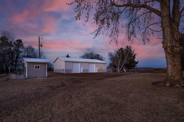 yard at dusk with a garage and an outdoor structure