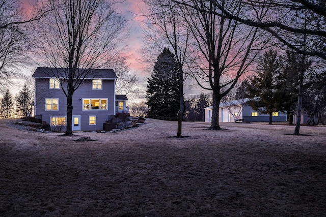 yard at dusk with a garage and an outbuilding