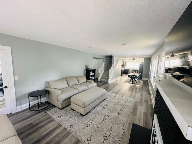 living room featuring ceiling fan, hardwood / wood-style floors, and a textured ceiling