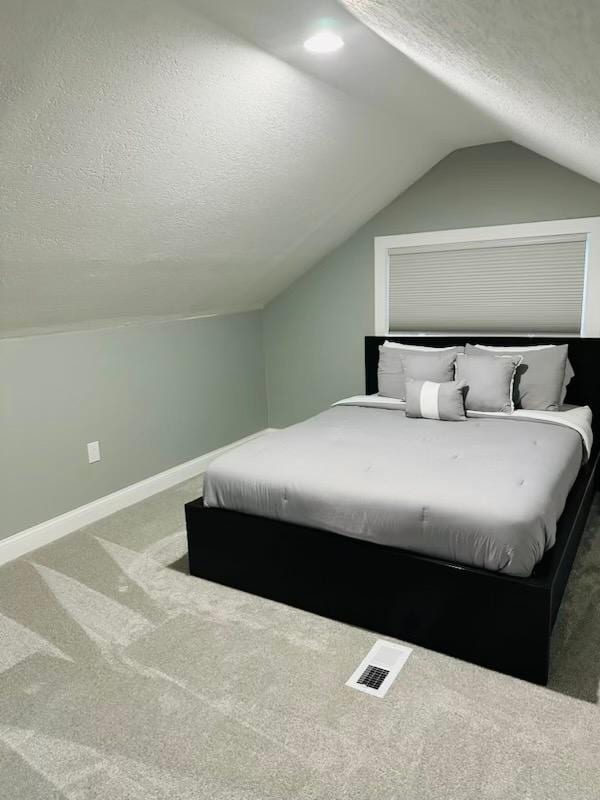 bedroom with lofted ceiling, carpet flooring, and a textured ceiling