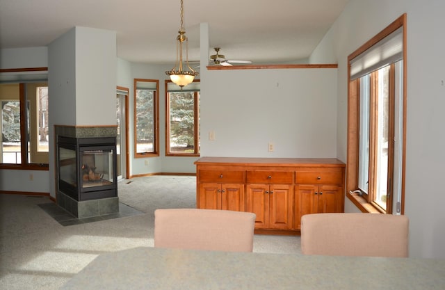 interior space featuring light carpet, hanging light fixtures, and a multi sided fireplace