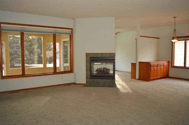 unfurnished living room featuring a tiled fireplace and light colored carpet