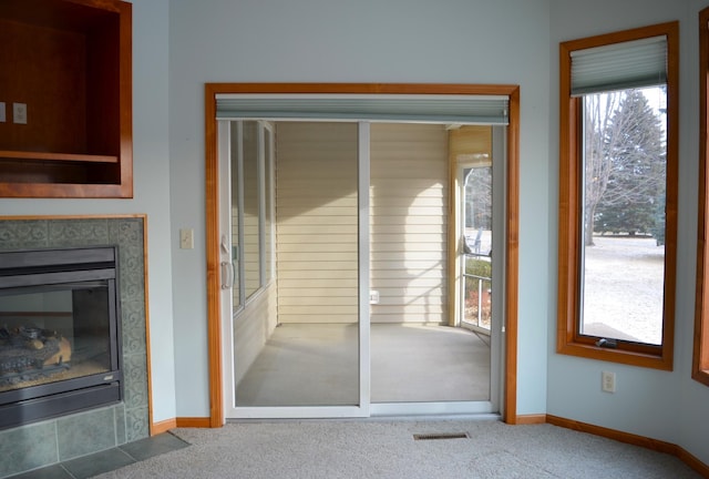 interior space featuring carpet flooring, a tiled fireplace, and a wealth of natural light