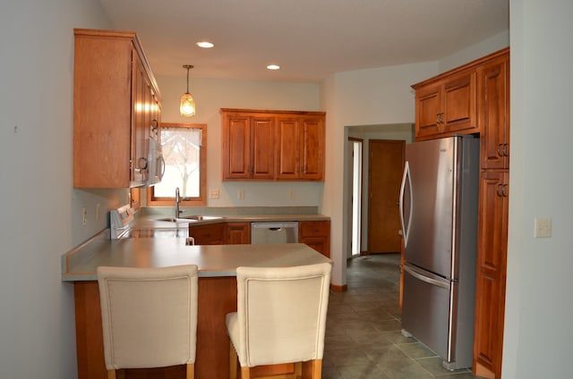 kitchen with sink, appliances with stainless steel finishes, a kitchen breakfast bar, decorative light fixtures, and kitchen peninsula