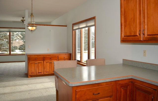 kitchen with plenty of natural light, decorative light fixtures, light colored carpet, and kitchen peninsula