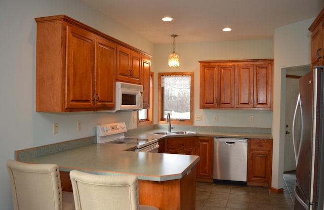 kitchen featuring sink, hanging light fixtures, stainless steel appliances, a kitchen bar, and kitchen peninsula