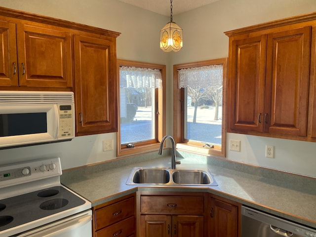 kitchen with pendant lighting, sink, white appliances, and a chandelier