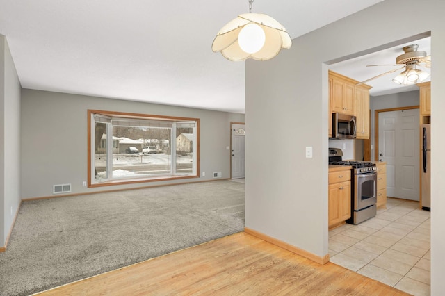 kitchen with ceiling fan, stainless steel appliances, light carpet, and light brown cabinets