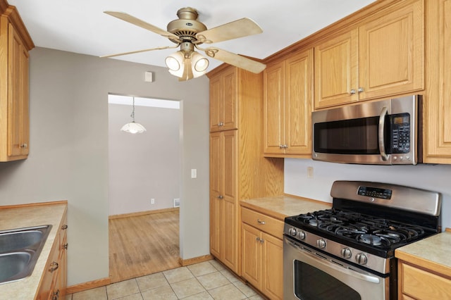 kitchen featuring light tile patterned floors, sink, ceiling fan, stainless steel appliances, and decorative light fixtures