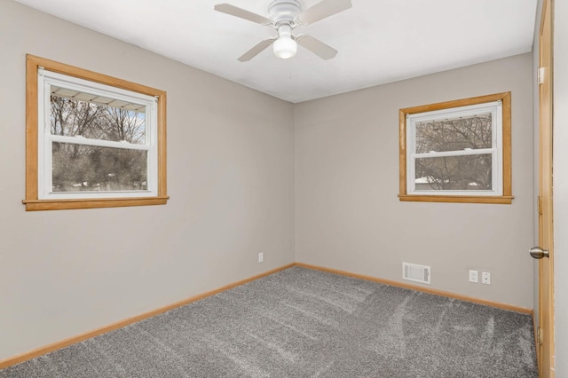 carpeted spare room featuring a healthy amount of sunlight and ceiling fan