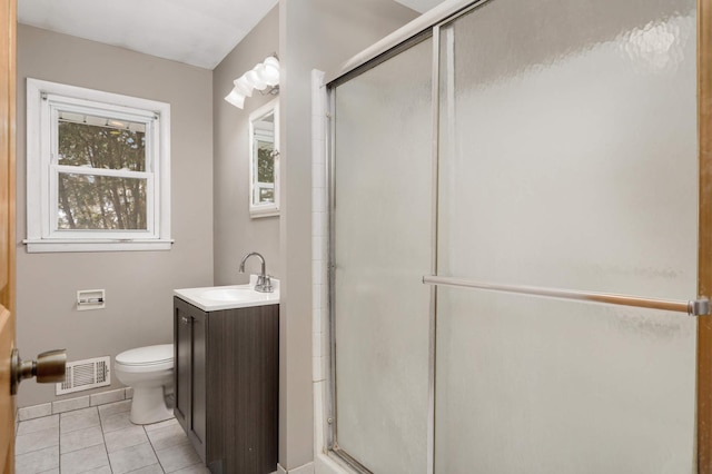 bathroom with tile patterned floors, vanity, toilet, and a shower with door