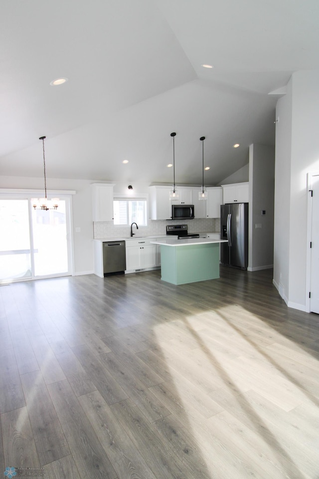 kitchen featuring decorative light fixtures, a center island, white cabinets, stainless steel appliances, and backsplash