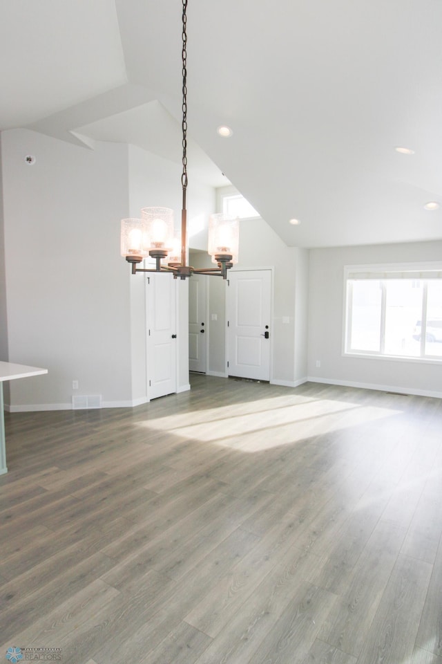 unfurnished living room with lofted ceiling, hardwood / wood-style flooring, and a chandelier