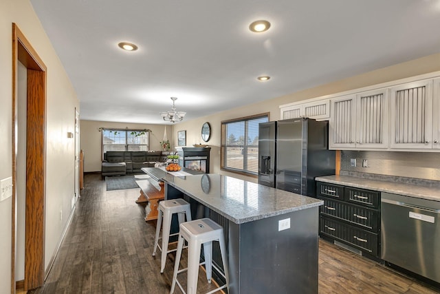 kitchen featuring dark wood-type flooring, stainless steel dishwasher, black fridge, and a center island