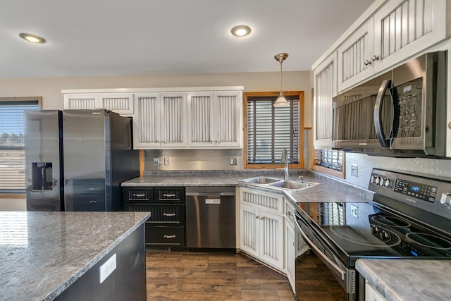 kitchen with dark wood-style flooring, a sink, appliances with stainless steel finishes, decorative backsplash, and decorative light fixtures