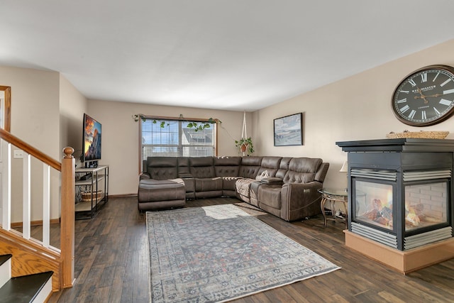 living room featuring stairs, baseboards, dark wood finished floors, and a multi sided fireplace