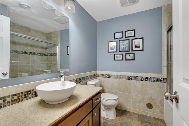 bathroom with toilet, vanity, visible vents, tile walls, and a stall shower