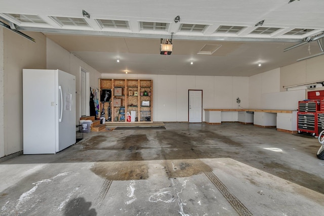 garage with a workshop area, freestanding refrigerator, and a garage door opener