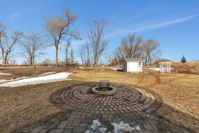 view of yard with a fire pit, a fenced backyard, an outbuilding, a storage unit, and a patio area