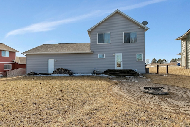 back of house featuring a fire pit, a gate, fence, and a yard