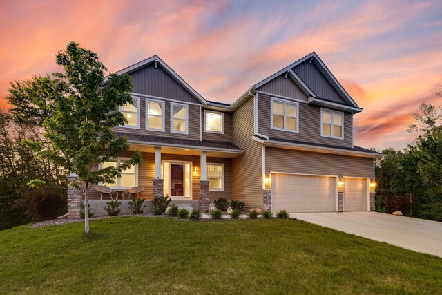 craftsman-style home with a garage, a lawn, and a porch