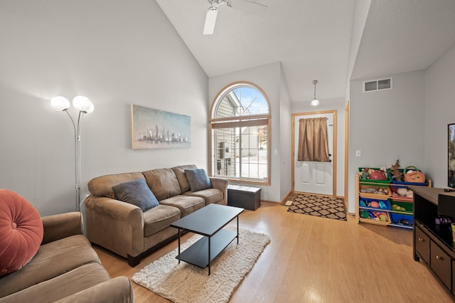 living room with ceiling fan, high vaulted ceiling, and light hardwood / wood-style flooring