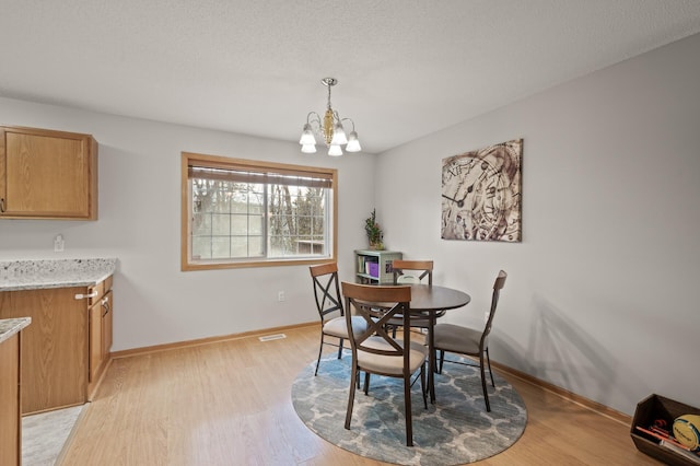 dining area featuring a textured ceiling, light hardwood / wood-style floors, and a chandelier