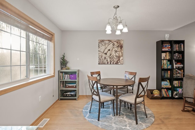 dining space with a notable chandelier and light hardwood / wood-style flooring