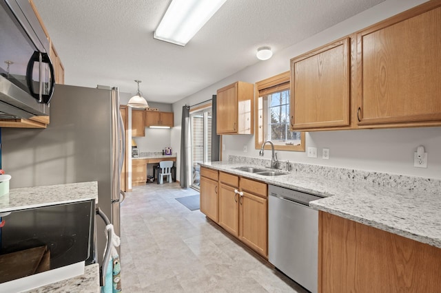 kitchen with decorative light fixtures, sink, light stone counters, stainless steel appliances, and a textured ceiling