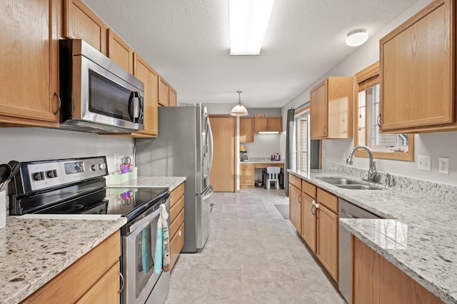 kitchen with sink, stainless steel appliances, light stone counters, a textured ceiling, and decorative light fixtures