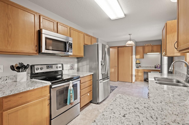 kitchen with sink, light stone counters, decorative light fixtures, a textured ceiling, and appliances with stainless steel finishes