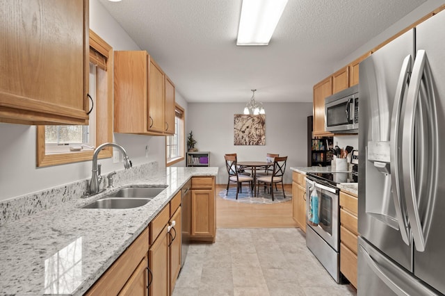 kitchen featuring pendant lighting, sink, appliances with stainless steel finishes, light stone counters, and a healthy amount of sunlight