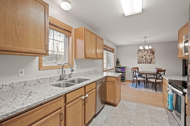 kitchen featuring sink, hanging light fixtures, light stone counters, kitchen peninsula, and stainless steel appliances