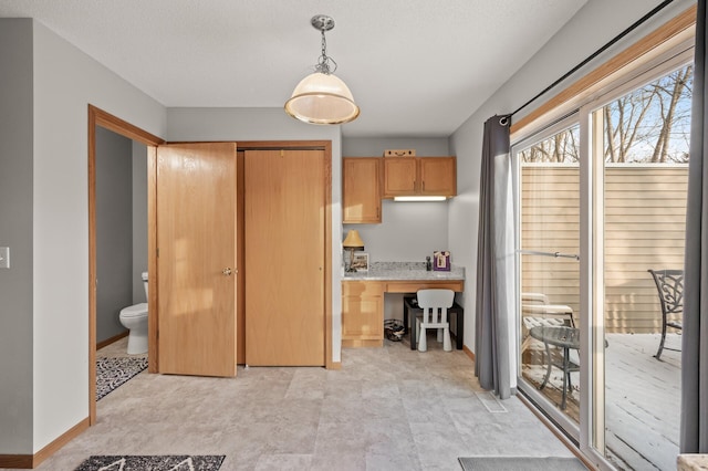 kitchen featuring hanging light fixtures, built in desk, and a textured ceiling