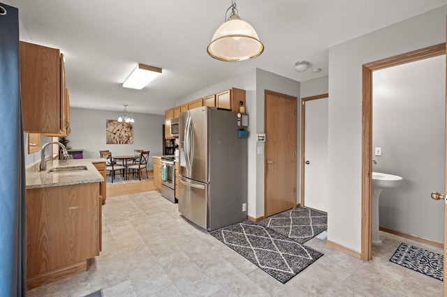 kitchen featuring pendant lighting, appliances with stainless steel finishes, light stone countertops, and sink