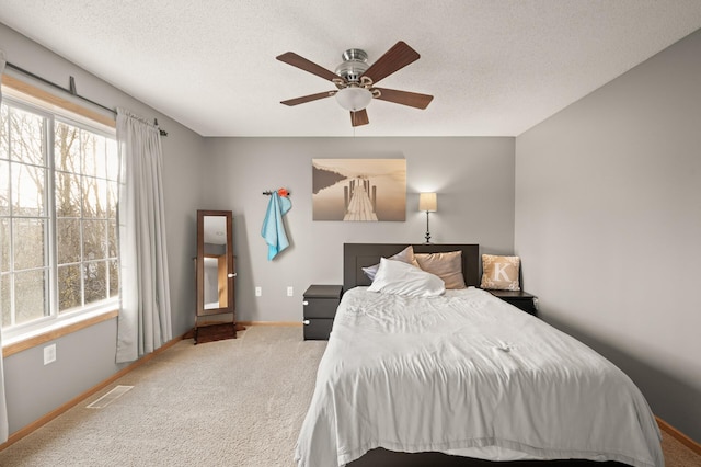 carpeted bedroom featuring ceiling fan and a textured ceiling