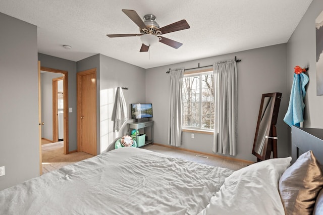 bedroom featuring ceiling fan, light colored carpet, and a textured ceiling