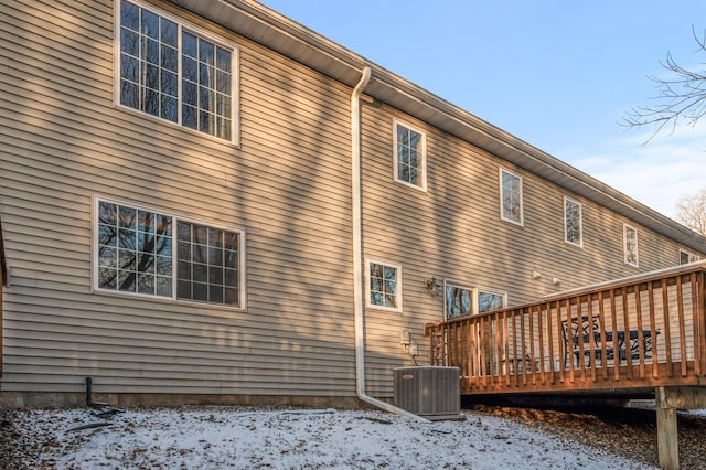 snow covered property featuring a wooden deck and central AC