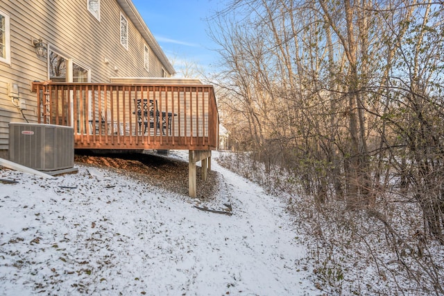 yard layered in snow with a wooden deck and central AC