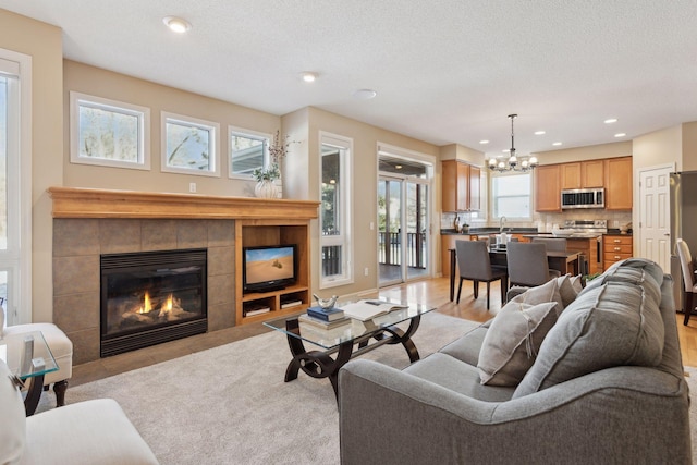 living room with sink, an inviting chandelier, a textured ceiling, and a fireplace