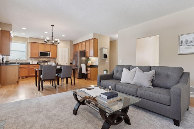 living room with sink, an inviting chandelier, and light wood-type flooring