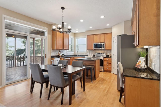 dining room with sink, light hardwood / wood-style flooring, and a notable chandelier