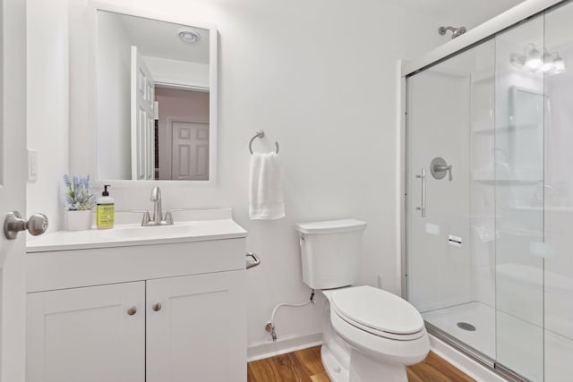 bathroom featuring an enclosed shower, vanity, wood-type flooring, and toilet