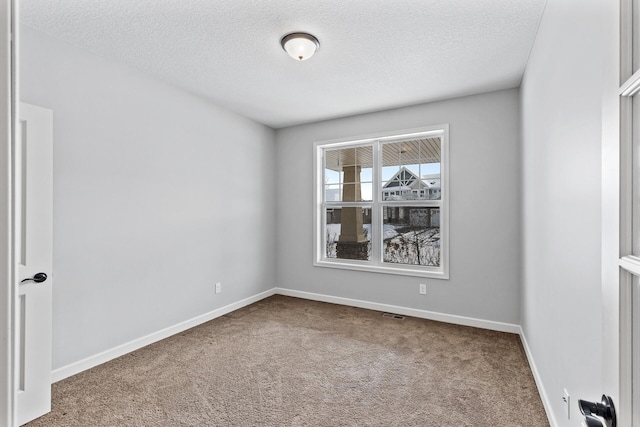 carpeted empty room featuring a textured ceiling