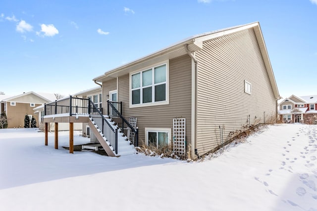 snow covered rear of property with a wooden deck