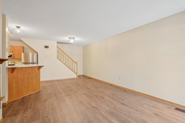 unfurnished living room featuring a textured ceiling and light wood-type flooring