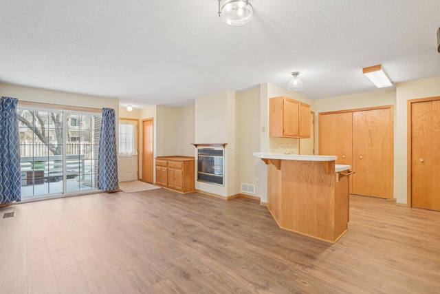 kitchen featuring light wood-type flooring, light brown cabinets, kitchen peninsula, and a breakfast bar