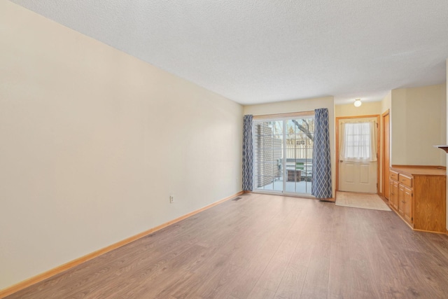 unfurnished room featuring a textured ceiling and light hardwood / wood-style floors