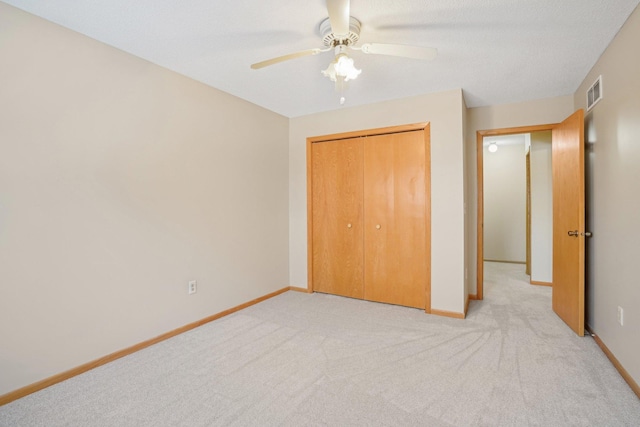 unfurnished bedroom featuring light carpet, a closet, and ceiling fan