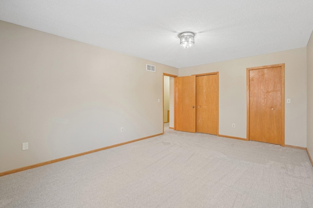 unfurnished bedroom featuring light colored carpet and a textured ceiling